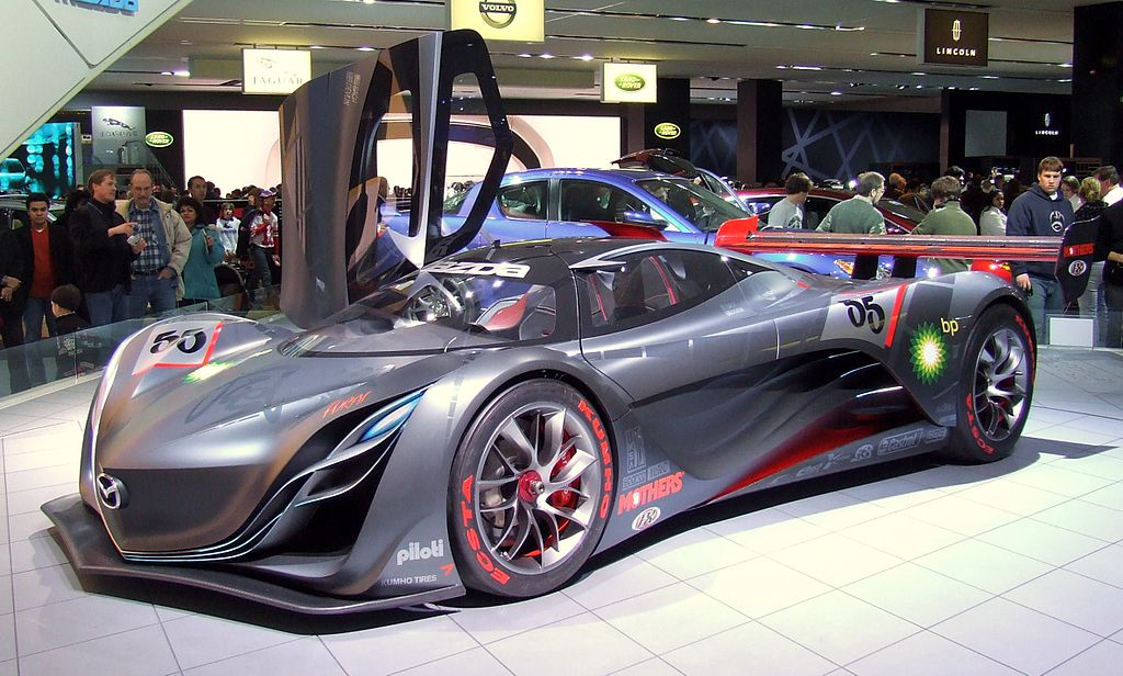 A photo of a sleek futuristic looking car on a show stage.