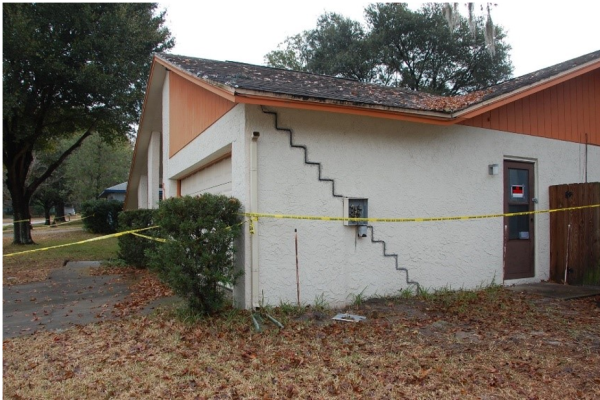 Photograph of the side of a house with a diagonal crack in the shape of steps running from the top left-hand corner of the wall to the ground on the right.